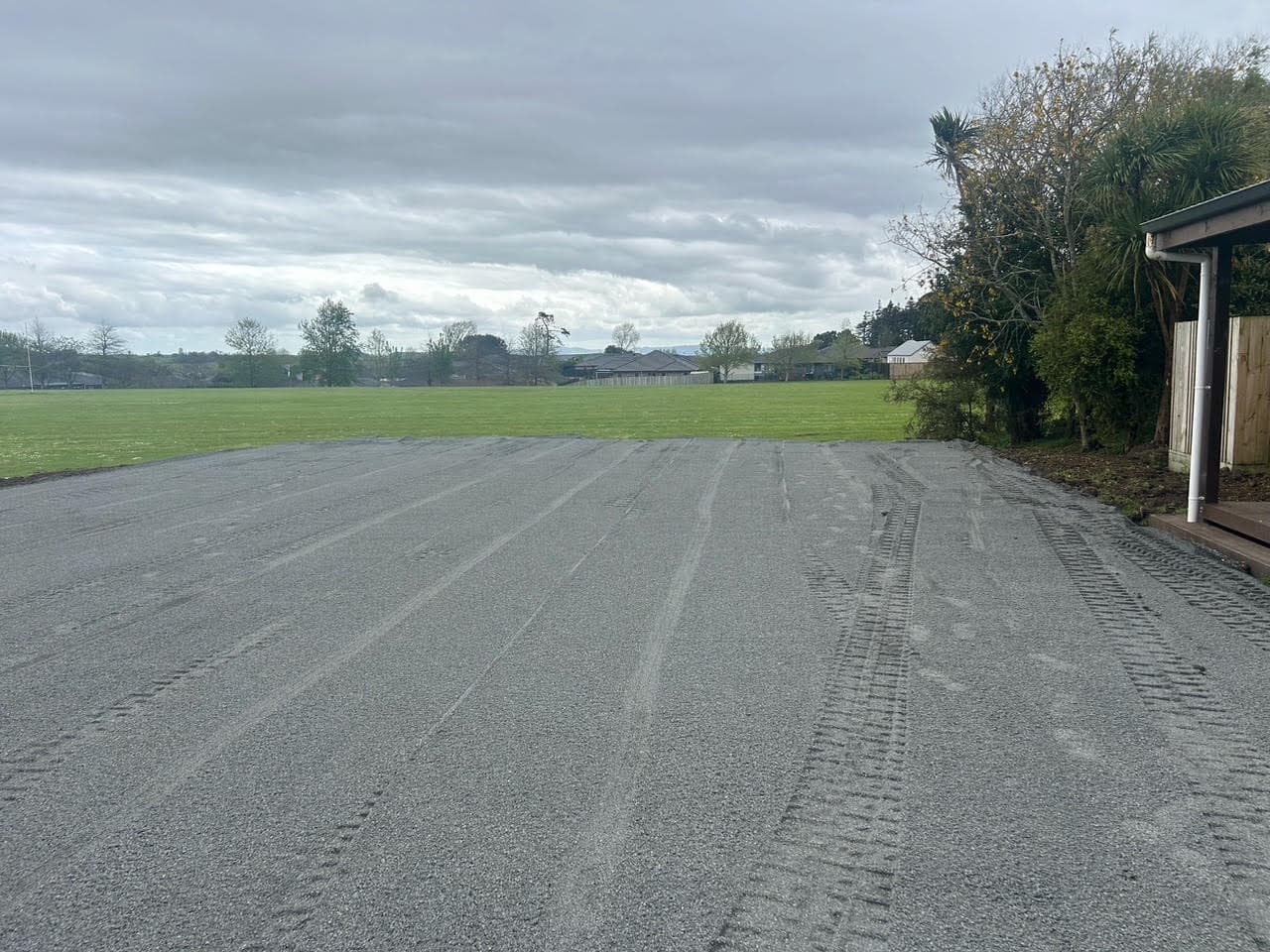 The same section finished as a metalled and rolled hardstand beside the house, sports field behind
