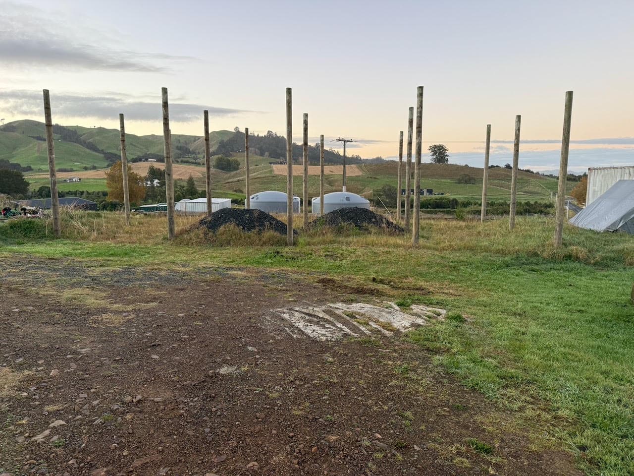 Pole shed poles set in the ground at first light, farmland and hills behind