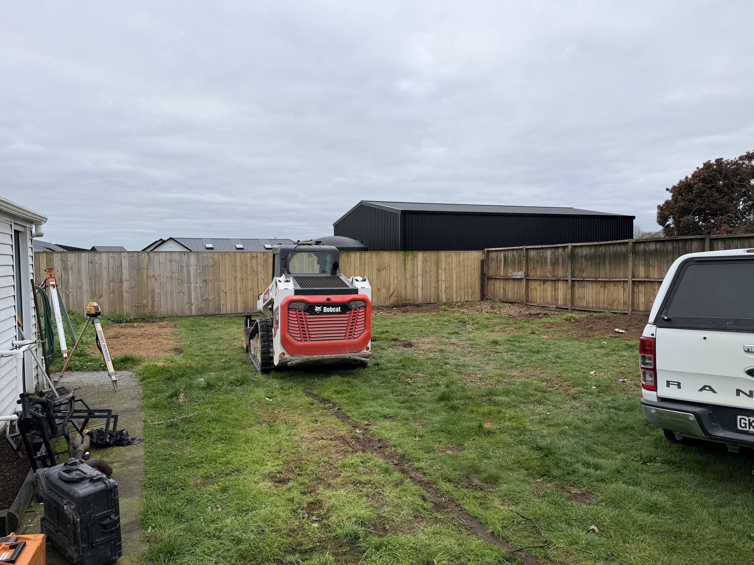 Track loader working a tight fenced backyard section with the laser level set up